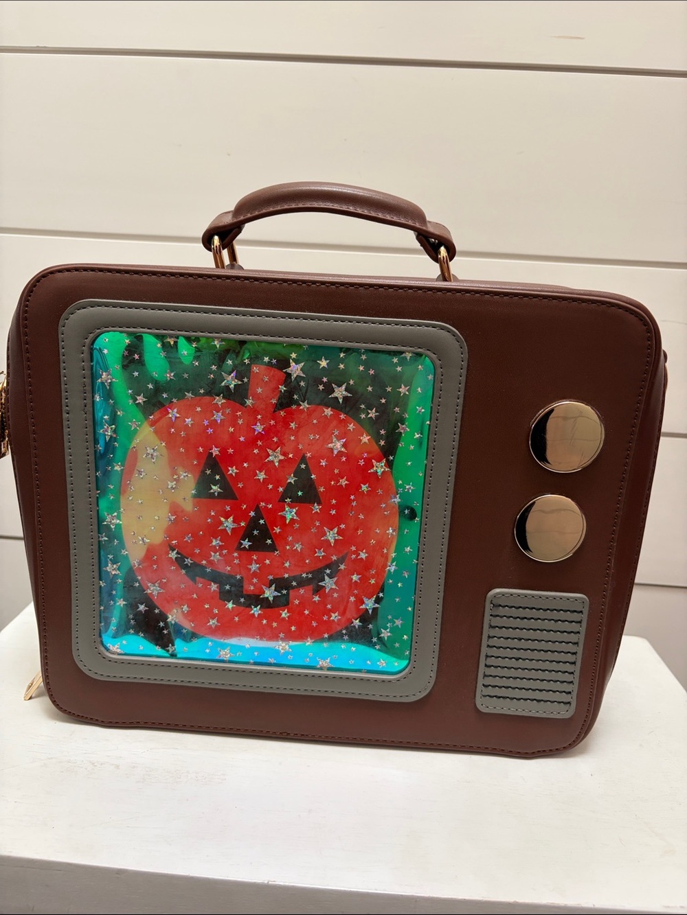 Backstitch Bruja Brown Crossbody Bag with Pumpkin TV screen.